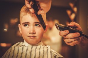 Little boy visiting hairstylist in barber shop
